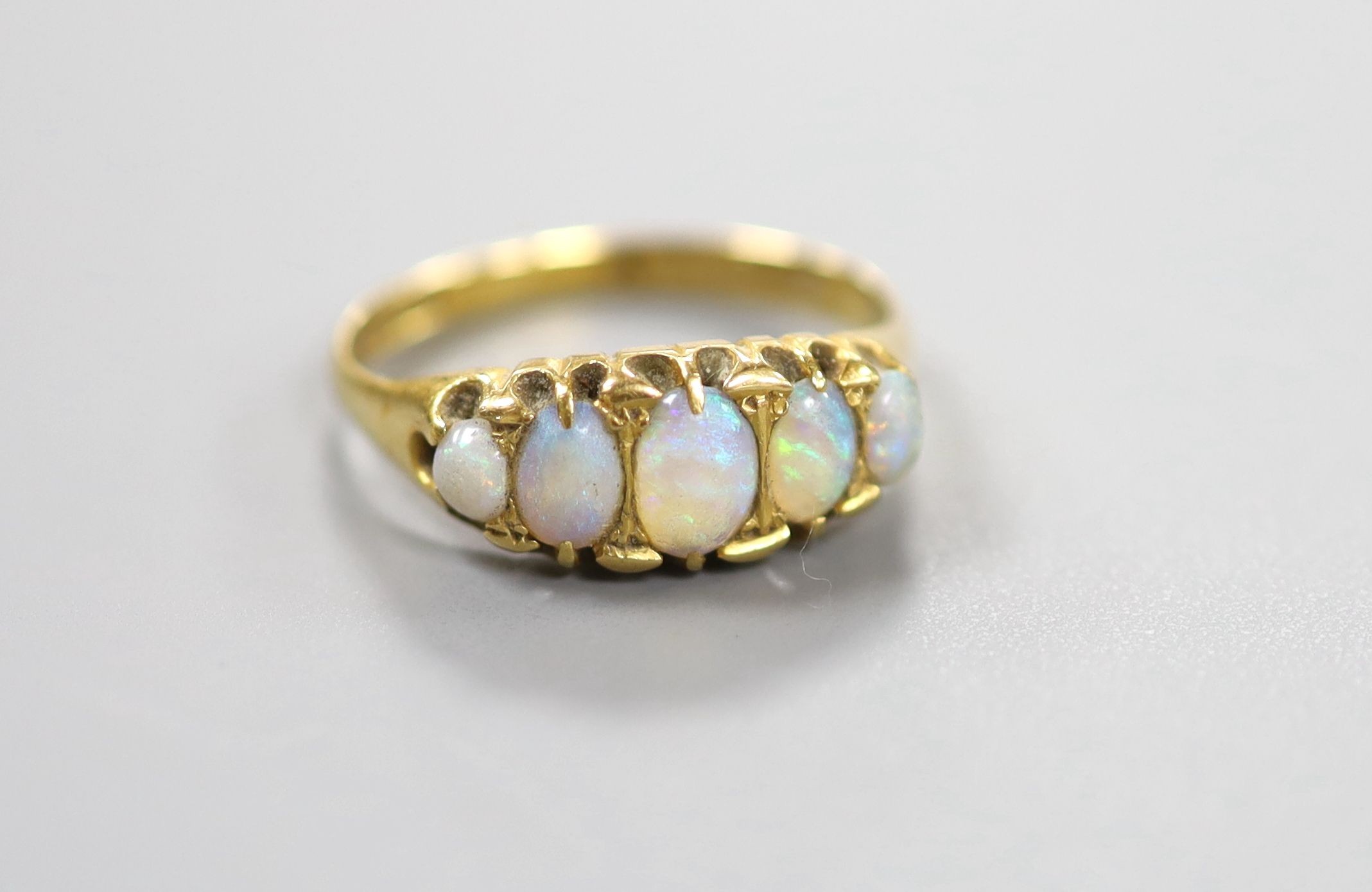 An 18ct gold and graduated oval white opal set half hoop ring, size Q/R, gross weight 3.4 grams.